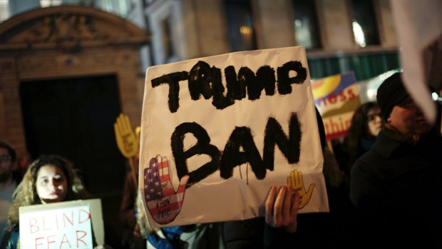 A man holds a placard during a gathering in Paris to protest US President Donald Trump's recent travel ban.