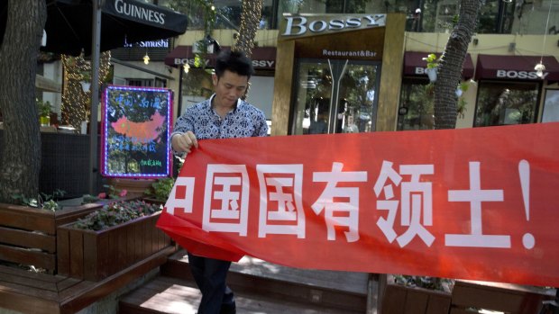 A restaurant worker puts up a banner which partly reads: "South China Sea is China's territory" in Beijing.