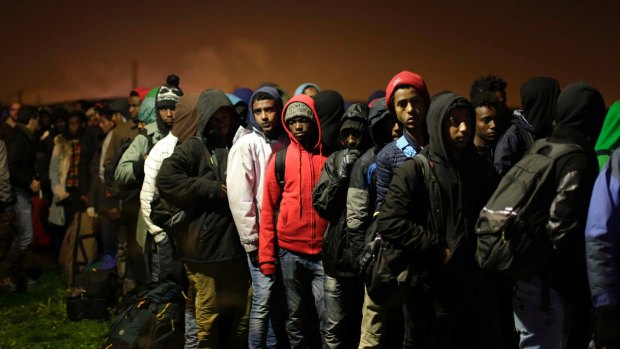 Migrants line up to register at a processing centre in the "Jungle" camp near Calais, early on Monday.