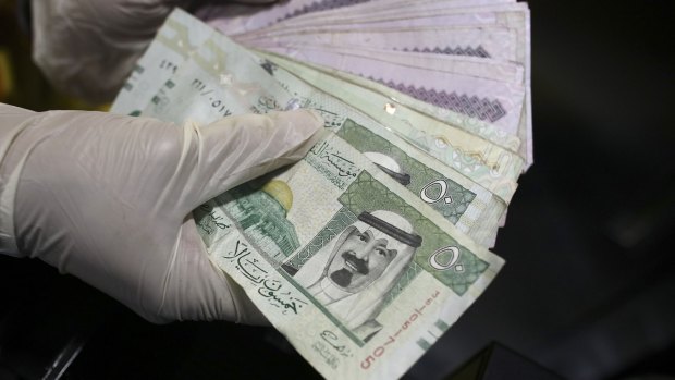 An employee counts a handful of Riyal banknotes from the cash till of a mobile burger van on the side of a highway in Riyadh, Saudi Arabia.