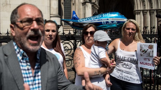 Supporters of Chris Gard and Connie Yates look on as Reverend Patrick Mahoney speaks to the media outside the High Court in London on July 10.