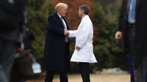 US President Donald Trump shakes hands with White House physician Dr Ronny Jackson as he leaves Walter Reed National Military Medical Center in Bethesda, Maryland, on Friday.