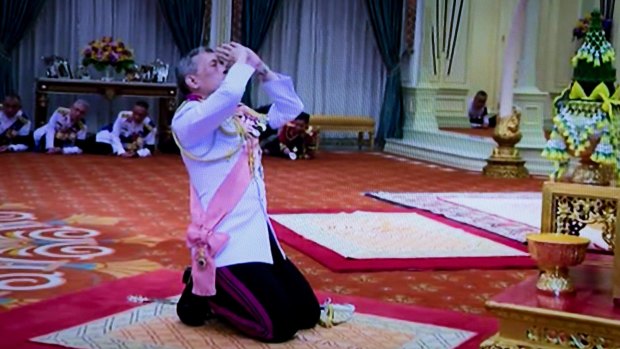 His Majesty King Maha Vajiralongkorn Bodindradebayavarangkun, or Rama X, kneels under a portrait of his late father at the Grand Palace in Bangkok, on Thursday.