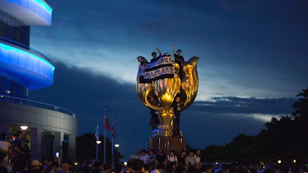 Pro-democracy activists shout slogans and hang a banner reading "Release Liu Xiaobo unconditionally, Hong Kong people want genuine universal suffrage", on Hong Kong's Golden Bauhinia monument, a gift from Beijing in 1997.