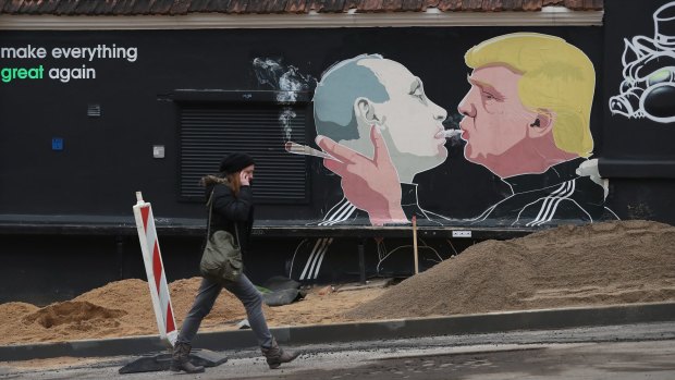 A young woman walks past a mural showing US President-elect Donald Trump blowing marijuana smoke into the mouth of Russian President Vladimir Putin in Vilnius, Lithuania.  