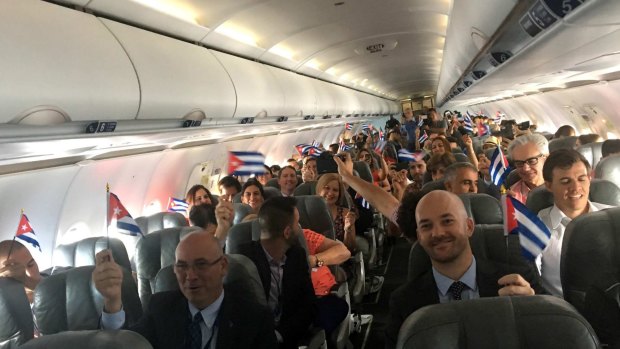 The first passengers from the US hold up Cuban flags, before touching down at the airport in Santa Clara, Cuba, on Wednesday.
