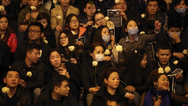 Chinese immigrants hold white roses as they gather to protest over the fatal shooting of Shaoyao Liu by police in his apartment in Paris.