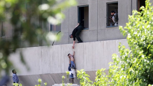 A child is lowered from a window in the Iranian parliament building following an attack on June 7.