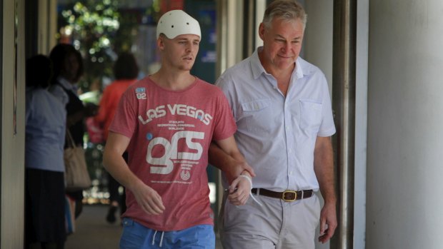 One-punch attack: Michael McEwen leaves hospital with his father, Robert.