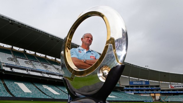 Graham Arnold is seen behind the A-League trophy at Allianz Stadium.
