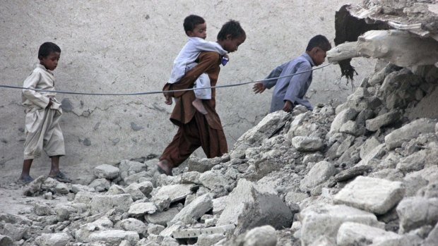 Survivors of Pakistan's 2013 quake walk through the rubble in Awaran.