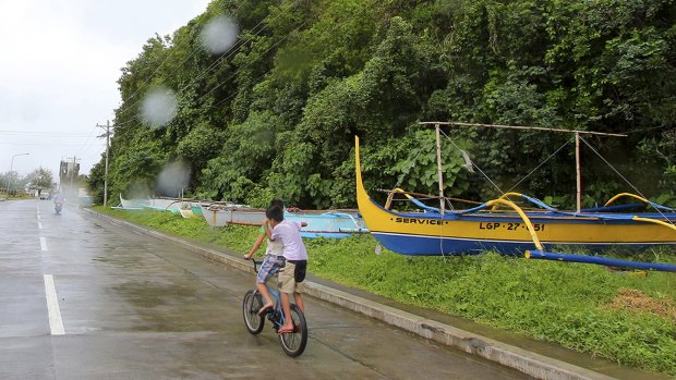 Boys ride a bike past boats placed on a safer area in Legazpi city, central Philippines as Typhoon Melor slammed into the eastern Philippines on Monday.