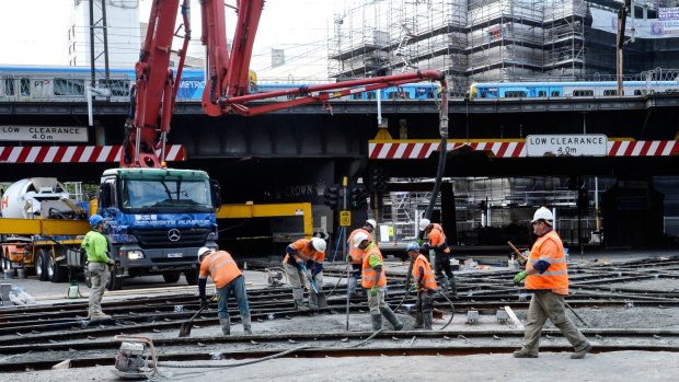 Workers build a new tram stop near the corner of Flinders and Spencer streets.