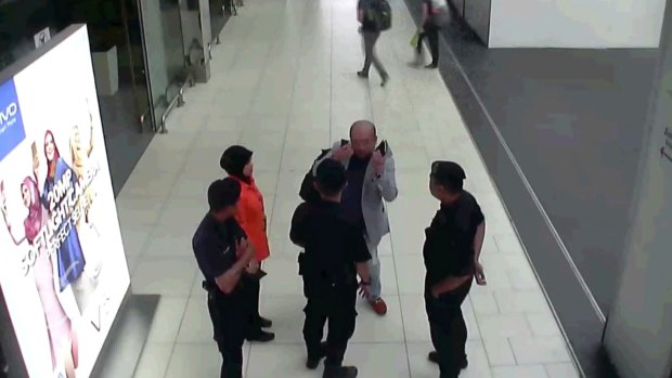 Kim Jong-nam, in grey, gestures towards his face while talking to airport security shortly before his death.