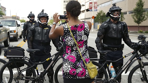 A demonstrator takes a picture of the police bicycle line.