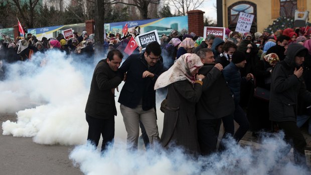 People run as riot police use tear gas and water cannons to disperse a crowd showing their support for the <i>Zaman</i> newspaper in Istanbul.