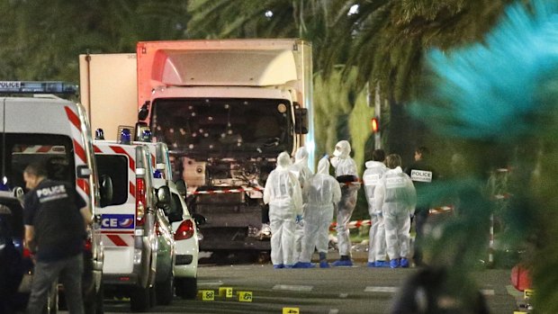 French police forces and forensic officers stand next to a truck that ran into a crowd in Nice.