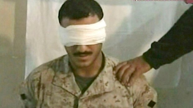 A screenshot of the video aired by Al Jazeera on June 27, 2004 shows a blindfolded man dressed in camouflage sitting in a chair with a hand holding a sword above his head and identified as US Marine Corporal Wassef Ali Hassoun. 