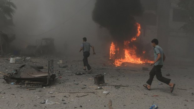 Locals try to escape the carnage after what observers say was a  Syrian government air strike on a local market near Damascus.