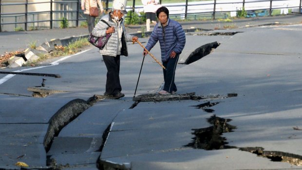 Residents stand on a split road in earthquake-hit in Mashiki, Kumamoto.