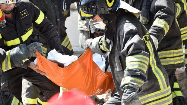 Rescue workers rescue a dead body in a damaged building in Accumuli.