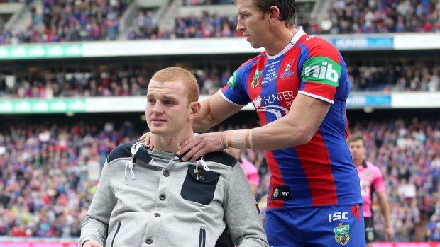 Kurt Gidley comforts Alex McKinnon before the start of the round 19 match between the Knights and the Titans.