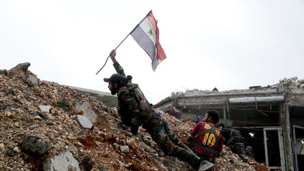 A Syrian army soldier places a Syrian national flag during a battle with rebel fighters at the Ramouseh front line, east of Aleppo.