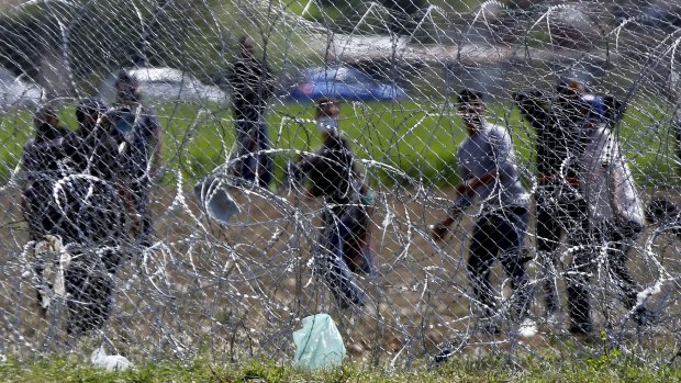 Unrest: Migrants throw stones from the Greek side of the border fence.