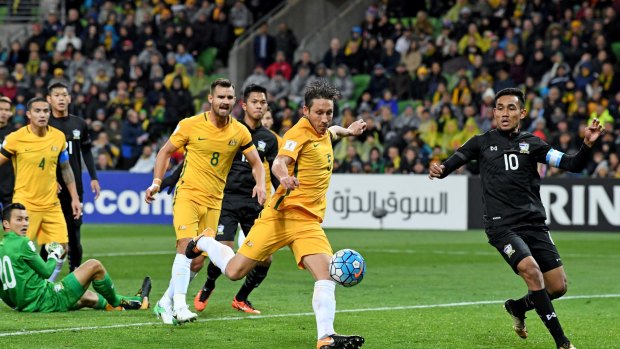 Patience please: Mark Milligan of the Socceroos strikes the ball but fails to break through.