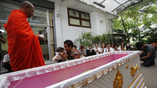A Buddhist monk performs a blessing at a hospital in Bangkok as Thai family members  pray around the coffin of a victim of the Erawan Shrine bombing.