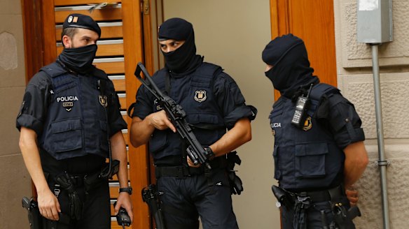 Police officers stand outside a building during a search in Ripoll, north of Barcelona.