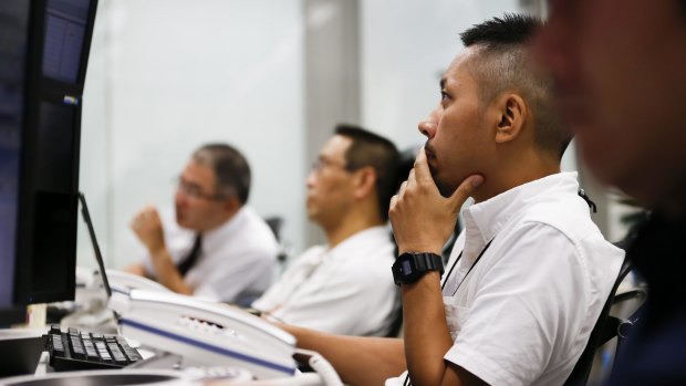 In shock: Employees work in front of computer monitors at a foreign exchange brokerage in Tokyo, Japan, on Friday.