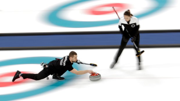 Russians Aleksandr Kruhelnitckii throws the stone as teammate Anastasia Bryzgalova looks on during their mixed doubles bronze medal curling match against Norway.