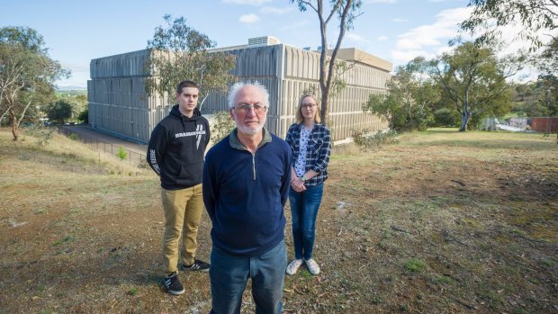Local resident association members George Barrows, and Michaela Cully-hugill stand with Red Hill Regenerators' Michael Mulvaney. Standing behind the old Telstra building where the redevelopment will take place, destroying bushland and placing future residents next to contaminated land.