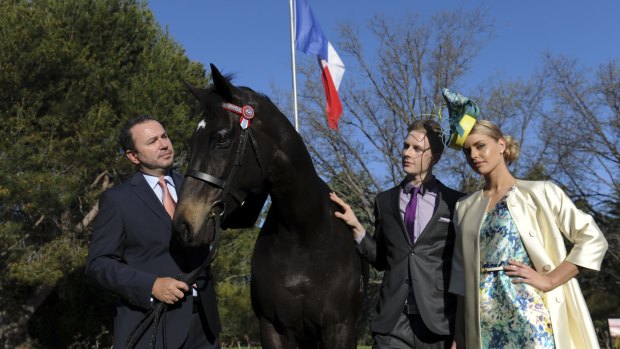 French Ambassador Christophe LeCourtier, left, holding "Casts a Shadow" with models Denzel Bruhn and Becky Patterson on the lawns of the French Embassy ahead of the Melbourne Cup preview event later this month.