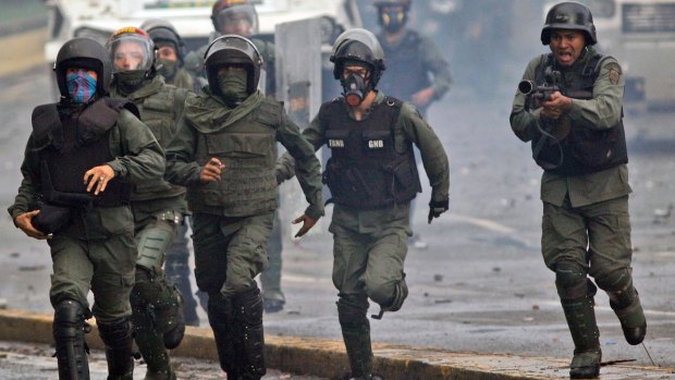 Bolivarian National Guards run and fire at anti-government demonstrators in Caracas, Venezuela.