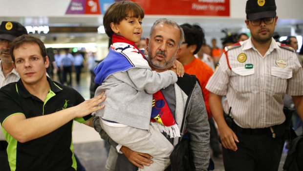 Syrian Osama Abdul Mohsen, centre, holds his son, Zaid, as they arrive at Barcelona train station on September 16.