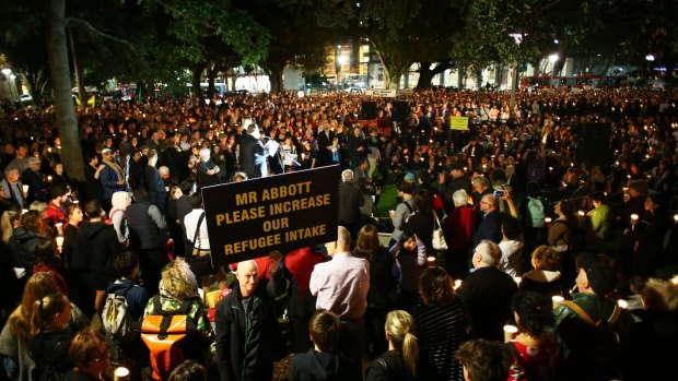 People hold candles and signs up in support of refugees in Sydney on Monday. 