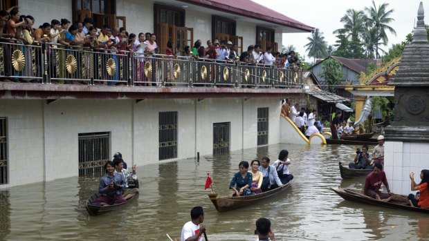 Myanmar opposition leader Aung San Suu Kyi, centre, rides a boat after visiting a monastery where flood victims are sheltered in Bago, Myanmar.