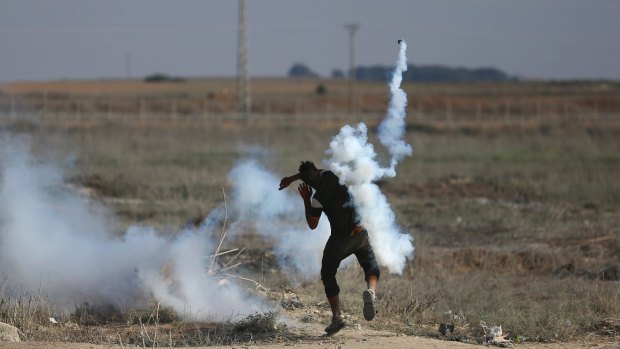 A Palestinian protester throws a teargas canister, originally fired by Israeli soldiers, back during clashes on the Israeli border with the Gaza Strip.