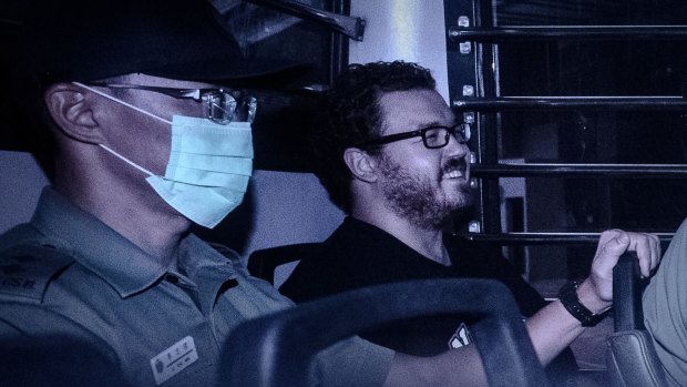 British banker Rurik Jutting, charged with the grisly murders of two women, smiles as he sits in a prison van leaving the eastern court in Hong Kong on Monday. 