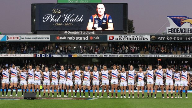 Crows players line up for a moment's silence to pay respect to their coach Phil Walsh after the round 15 match against the West Coast Eagles on Saturday.