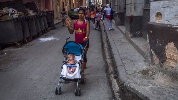 Pushing a stroller along a street in Old Havana. Few families are left untouched by the schism that followed the country's revolution.