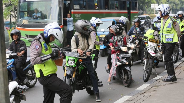 Motorcyclists, police and pedestrians share roads and footpaths in Jakarta, Indonesia