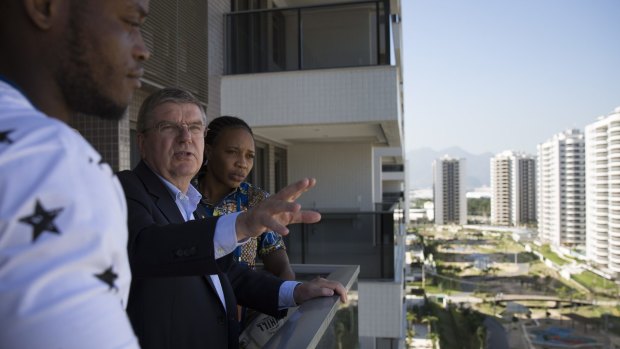 IOC president Thomas Bach, centre, talks with refugees and judo athletes from the Democratic Republic of Congo as they visit an apartment in the Olympic Village.