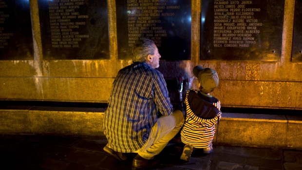 A man and a child places flowers at a Buenos Aires monument with names of Argentine soldiers killed during the Falklands war.