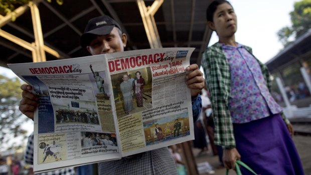 A man reads a newspaper featuring Myanmar's opposition leader Aung San Suu Kyi's meetings with President Thein Sein and General Min Aung Hlaing.