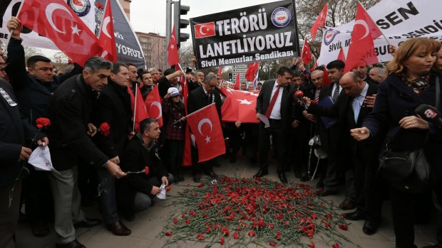 Turkish civil servants hold a banner that reads " we condemn terrorism " as they lay carnations at the site of Wednesday's explosion in Ankara.