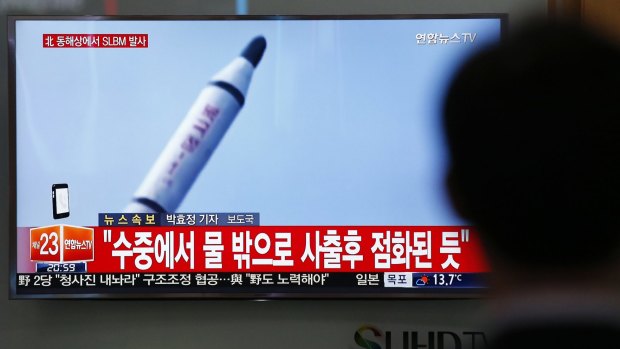 A man watches a TV news program showing footage of a missile launch conducted by North Korea.