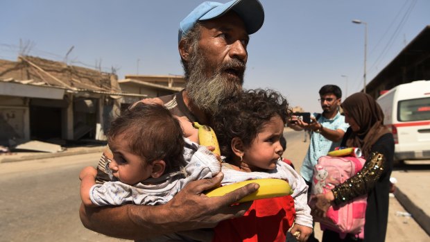 A man carries two children after being rescued from Islamic State in Mosul.